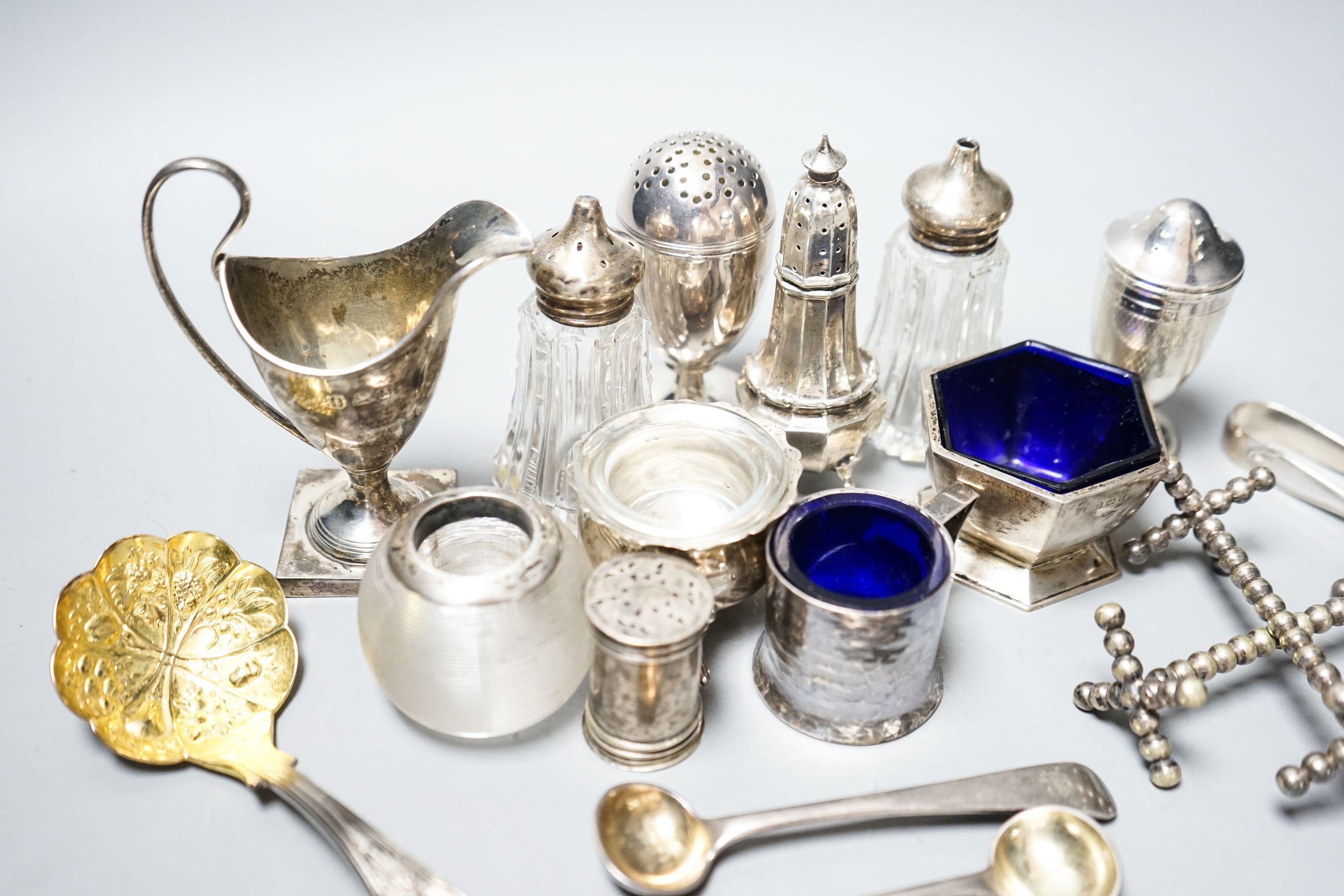 A group of small silver including condiments, match strike, cream jug, plated knife rests etc.